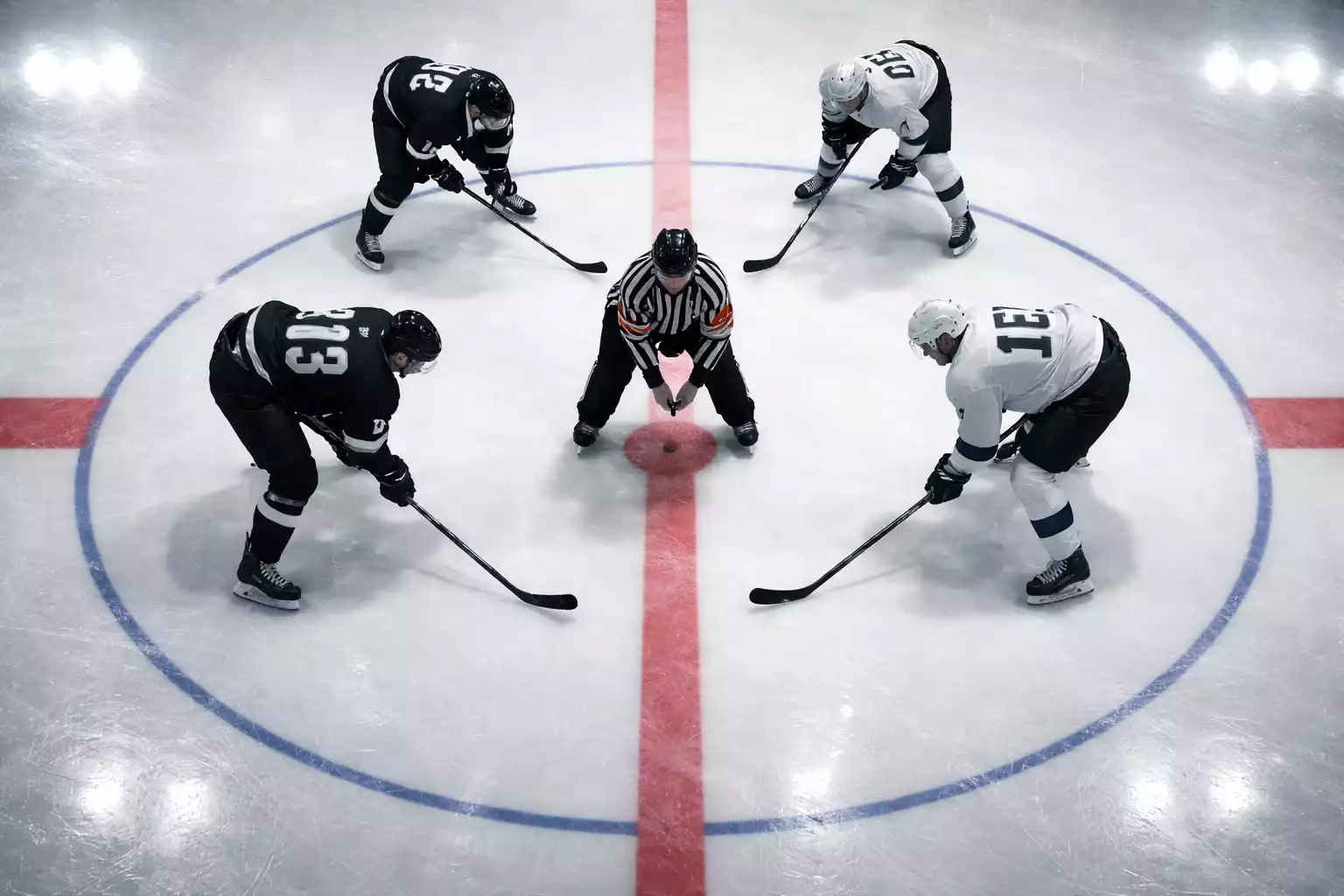 Eishockeyspieler beim Bully zu Beginn eines Drittels aus der Vogelperspektive